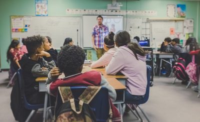 Students attentively listening to a teacher in a classroom setting