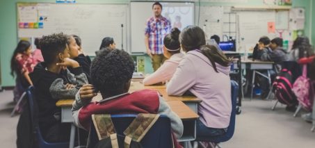 Students attentively listening to a teacher in a classroom setting