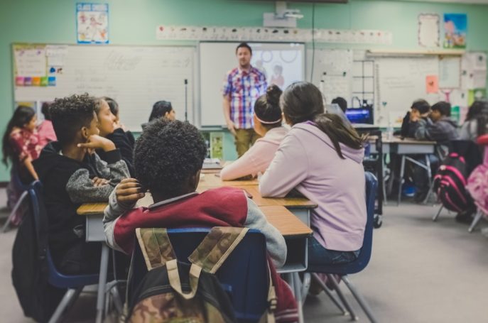 Students attentively listening to a teacher in a classroom setting